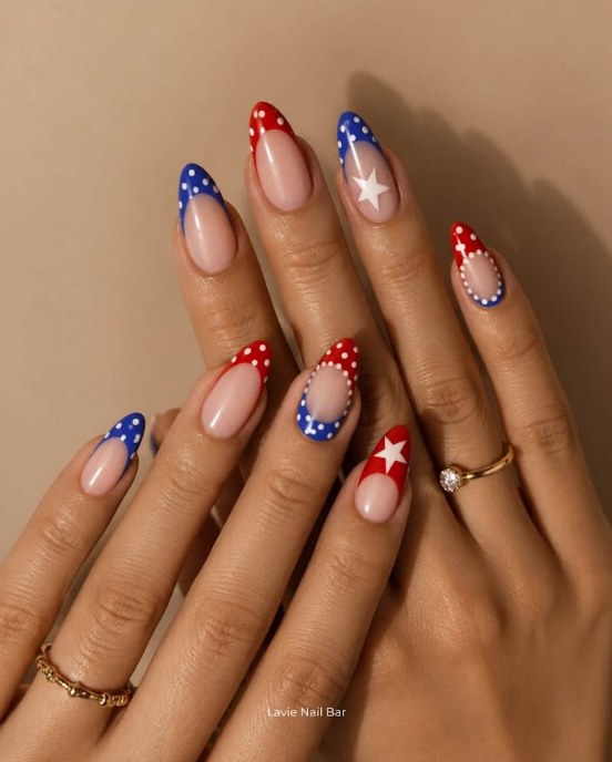 Close-up of almond-shaped nails with hand-painted white floral art and fine gold line accents, resting on a travertine stone slab in soft daylight